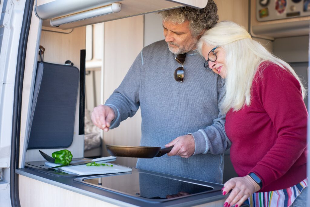 A couple enjoying some time cooking together in a caravan with all the necessary equipment